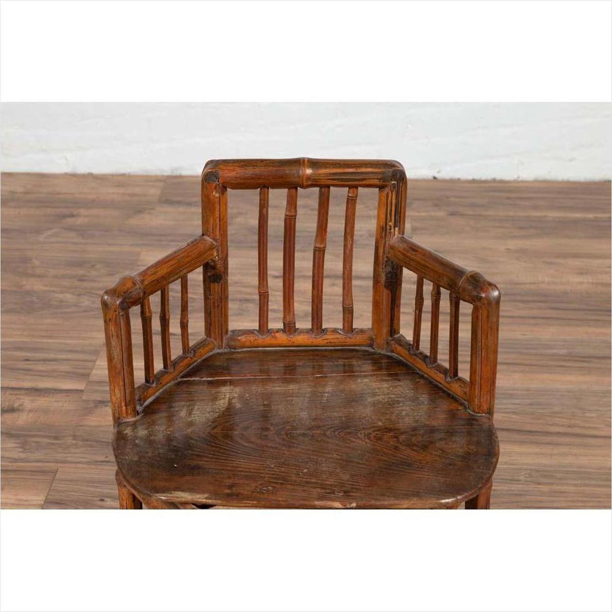 Brown bamboo child's corner chair with hexagonal base on a wooden floor next to a white wall indoors.
