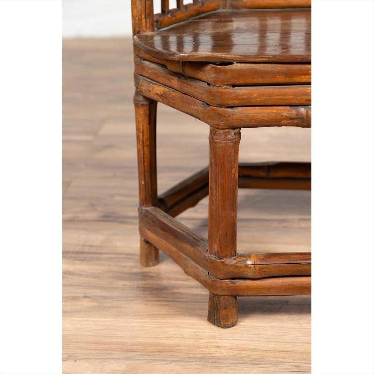 Close-up of brown bamboo and wood child’s corner chair with hexagonal base on light wood floor.