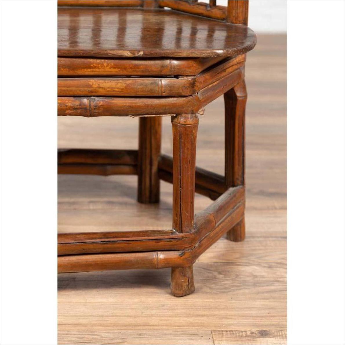 Close-up of brown bamboo Chinese antique child's corner chair with hexagonal base on light wood floor.
