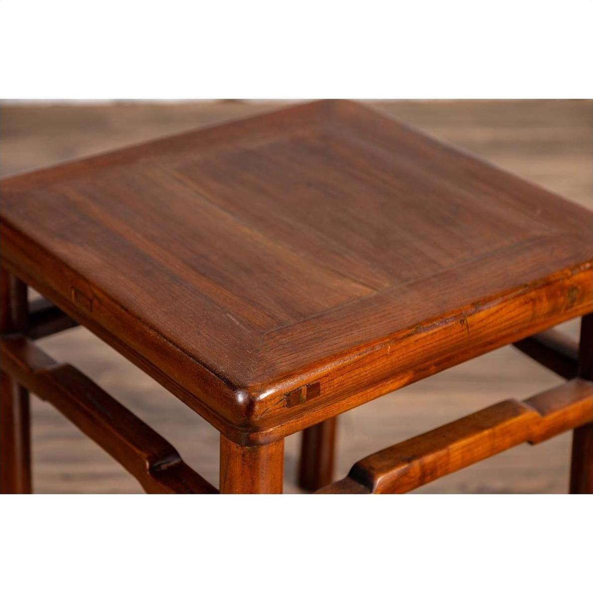 Close-up of brown wood Chinese Ming style side table with humpback stretcher on a wooden floor.