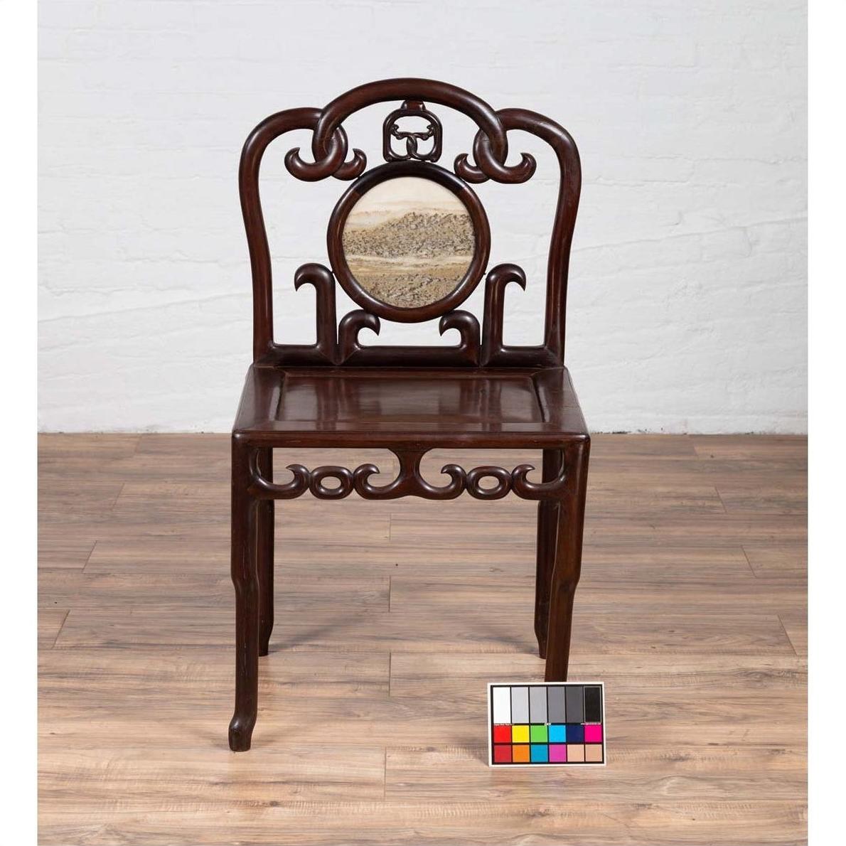 Dark rosewood Chinese antique side chair with open fretwork and marble medallion on a wooden floor.