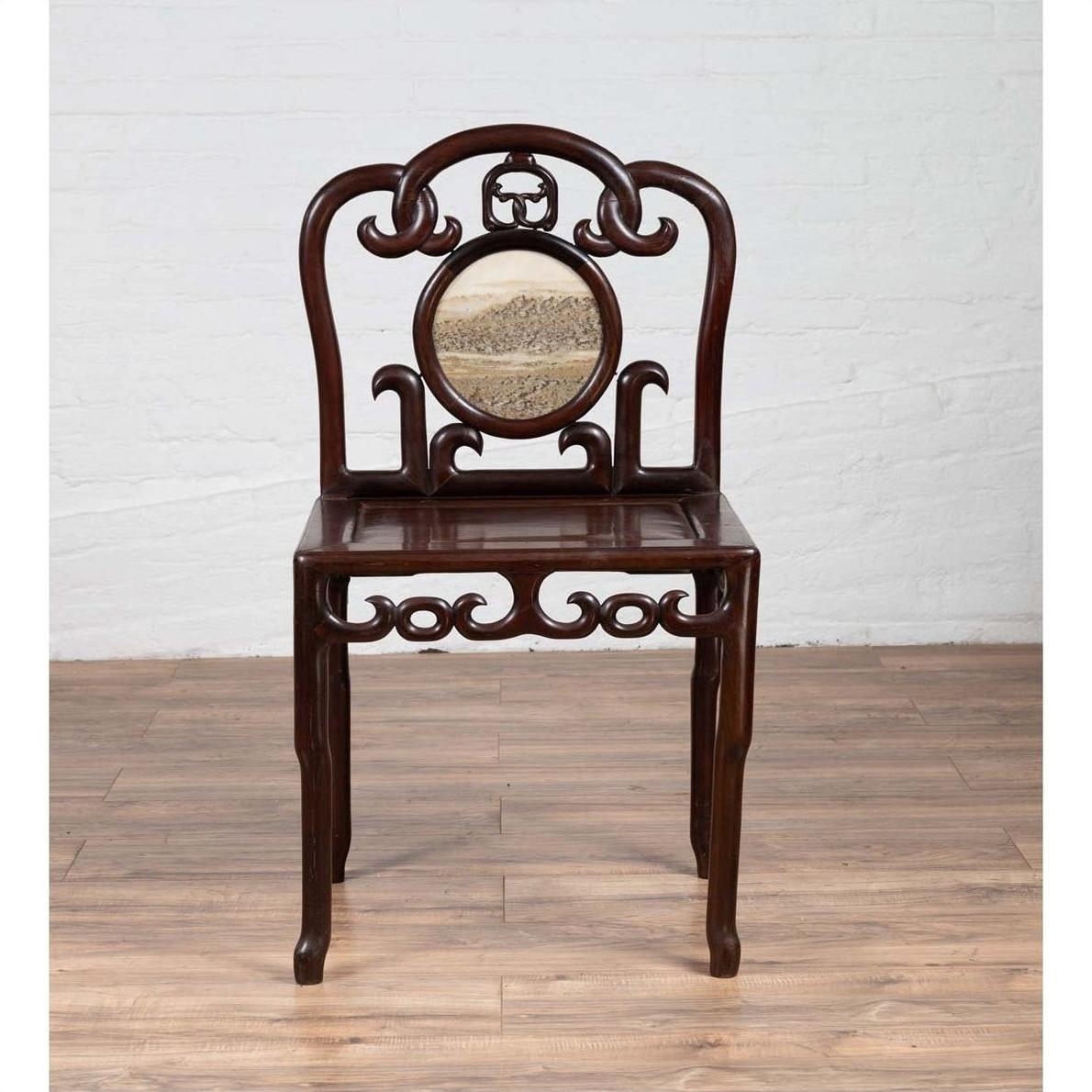 Dark rosewood antique side chair with open fretwork and marble medallion, on a wooden floor.