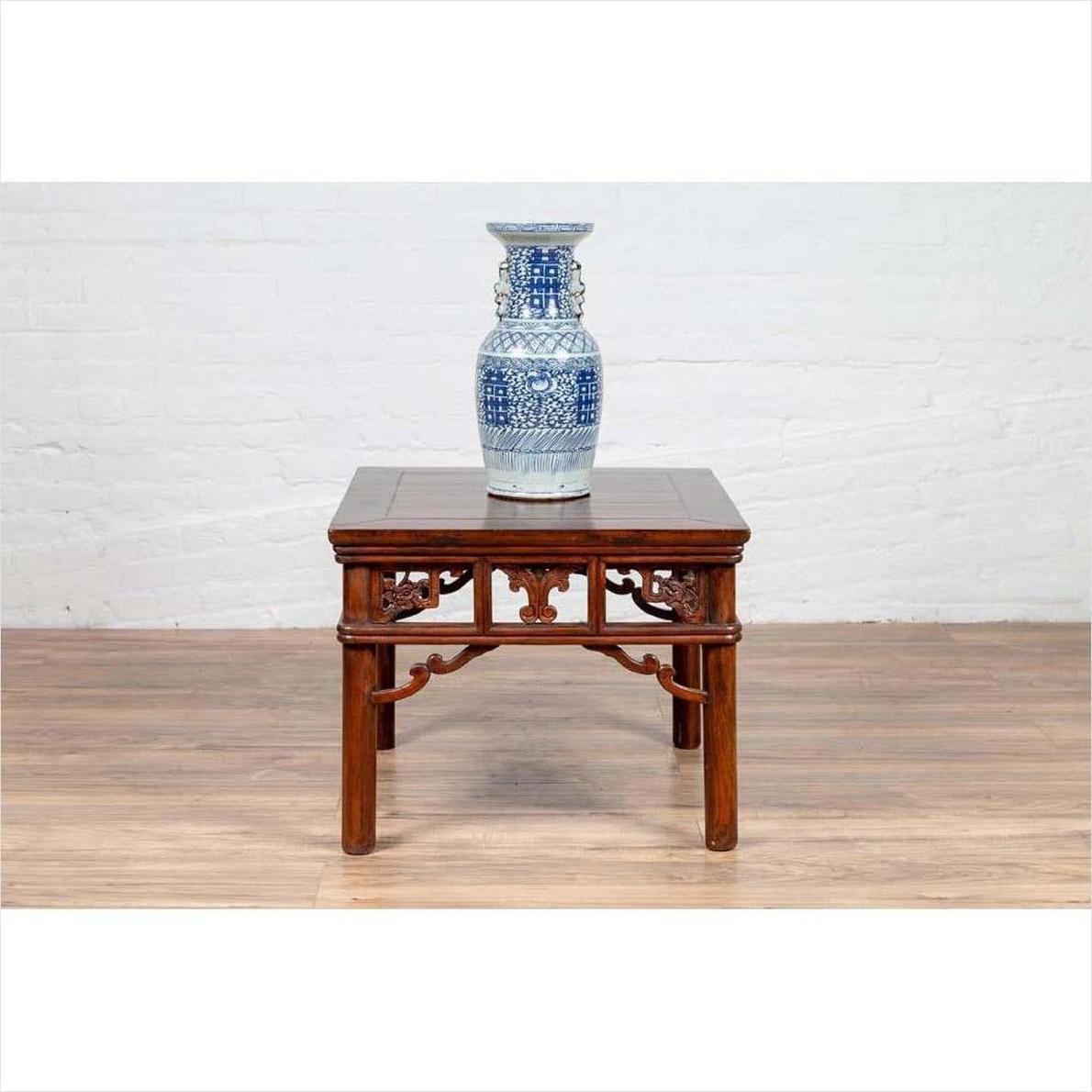 Blue and white ceramic vase on dark wood Chinese antique side table with open fretwork design, close-up view.