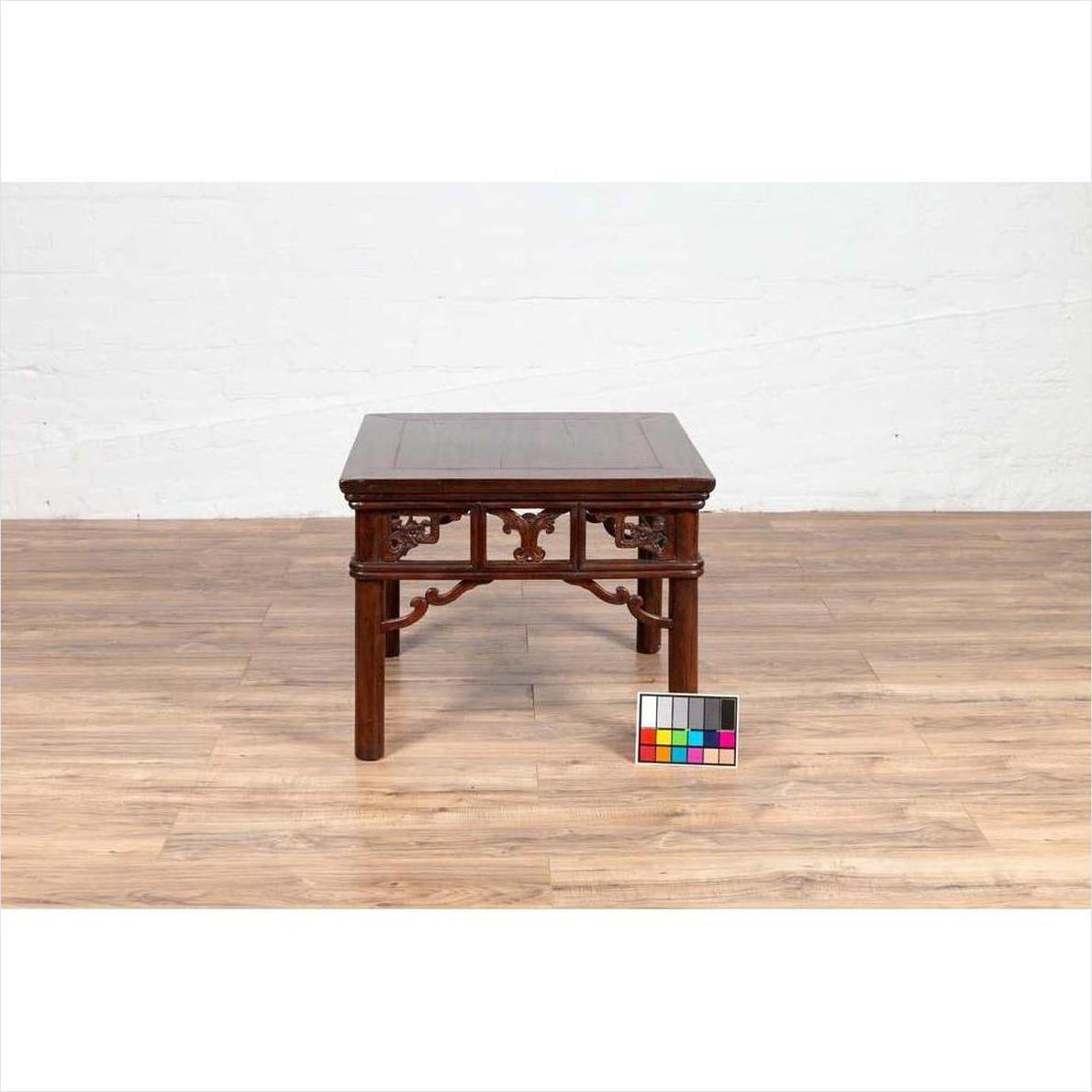 Dark wood Chinese antique side table with open fretwork design, on wooden floor, color card in front.