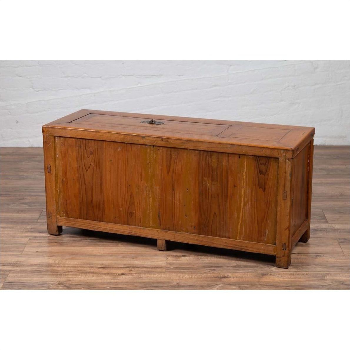 Brown wood two-door Chinese antique buffet with faux doors and removable upper panel on wooden floor by white brick wall.