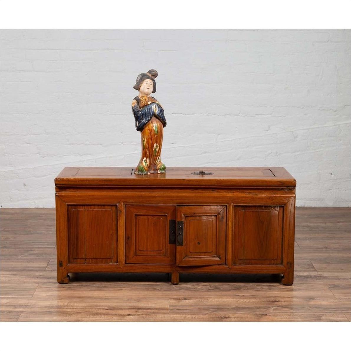 Brown wood two-door Chinese antique buffet with faux doors and removable panel, topped with ceramic figurine.