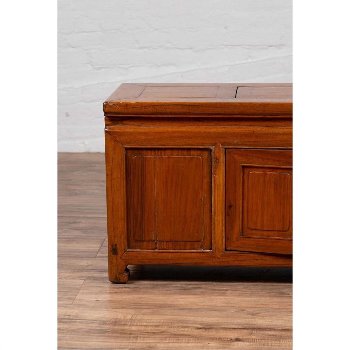 Close-up of a brown wood antique two-door buffet with faux doors and upper removable panel on a wood floor indoors.