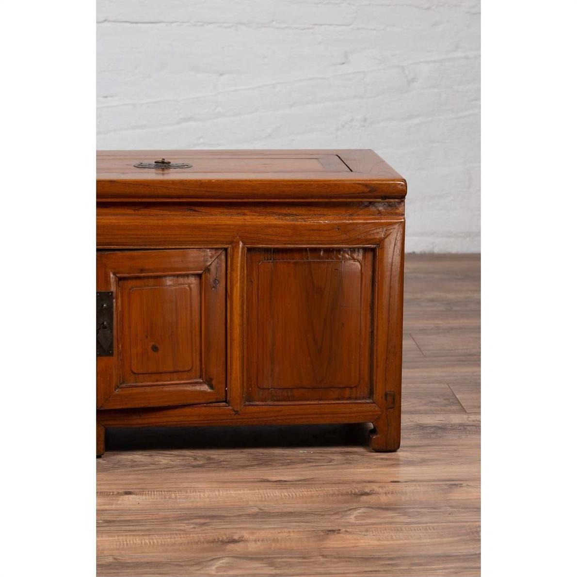 Brown wood two-door antique buffet with faux doors and removable upper panel on wooden floor by white brick wall indoors.