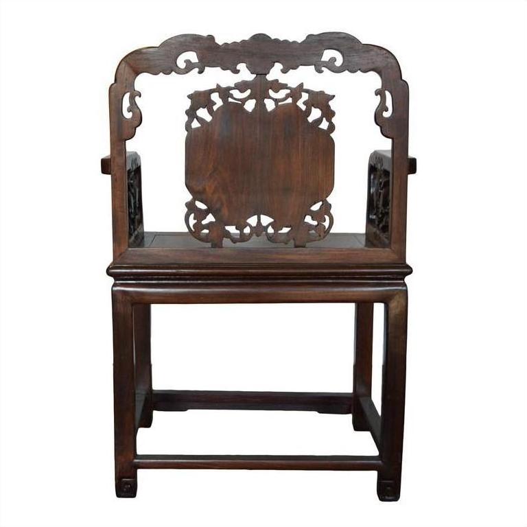 Brown carved rosewood Chinese chair with ornate backrest and armrests, front view on white background.