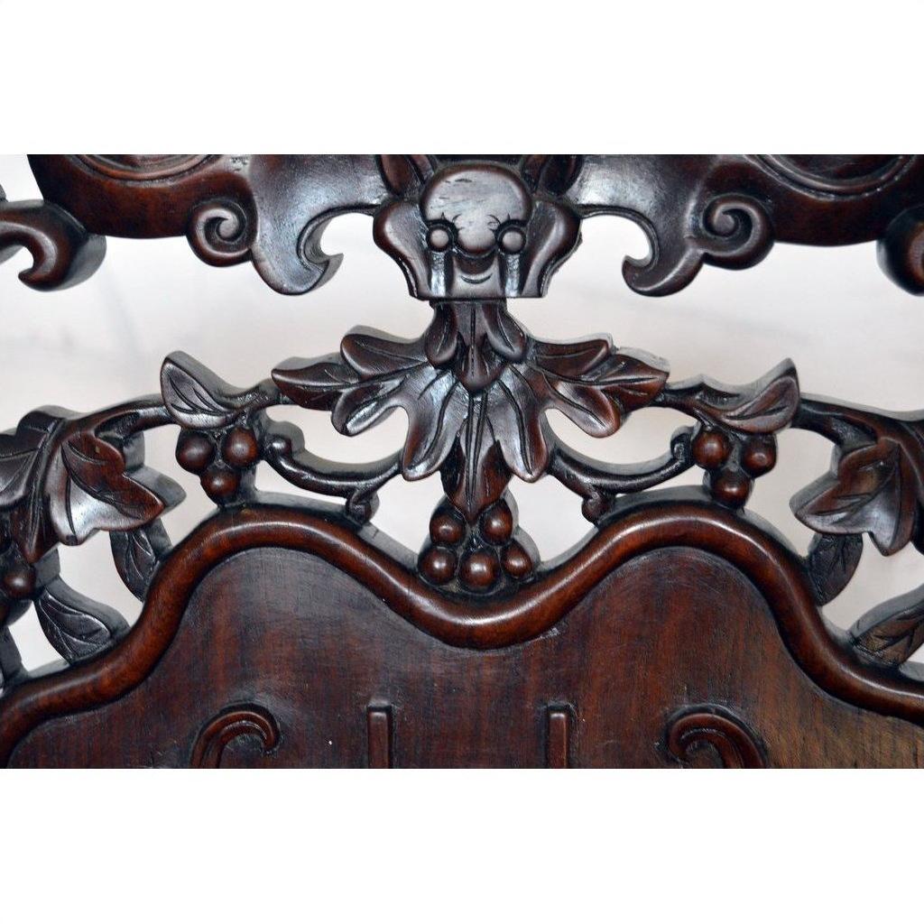 Dark rosewood Chinese chair with ornate floral carvings and central skull motif, early 20th century, front view.