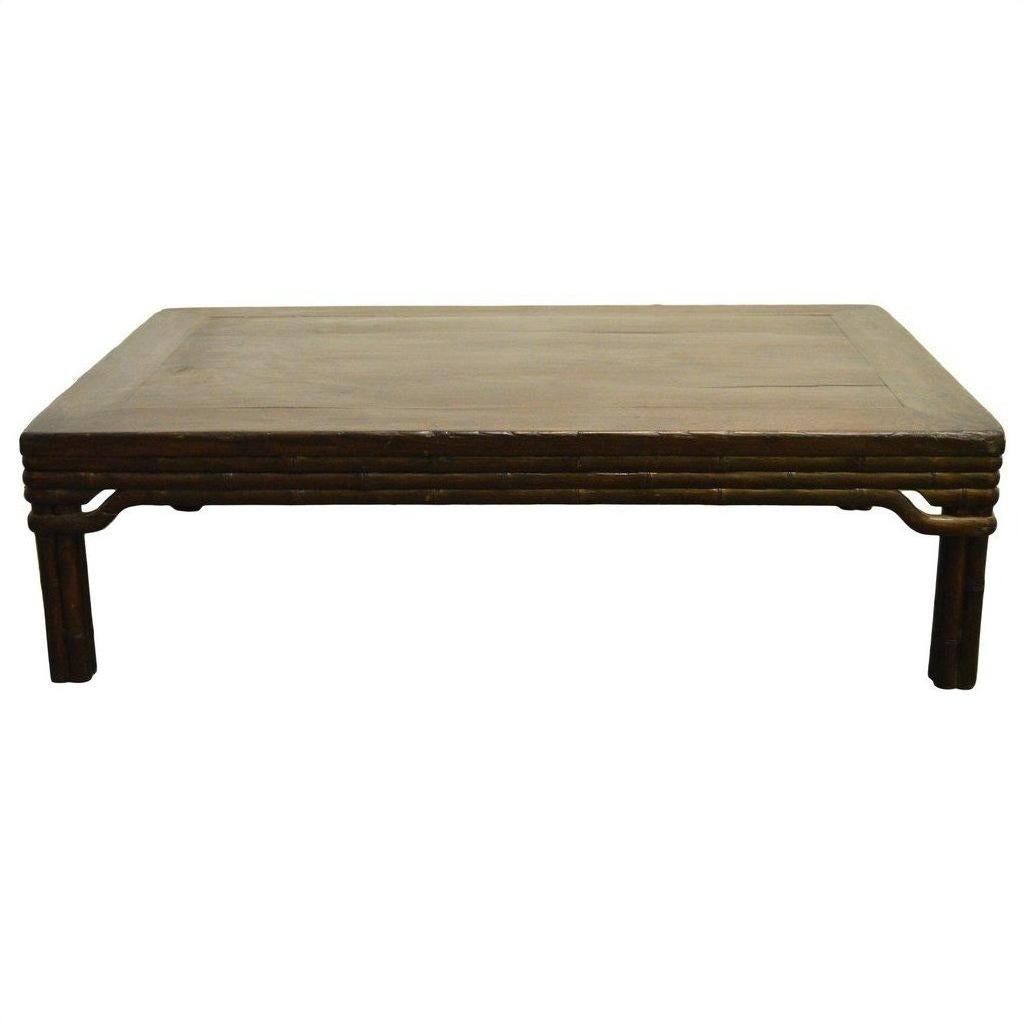 Brown wood Chinese coffee table with carved friezes, rectangular top, and short sturdy legs against white background.