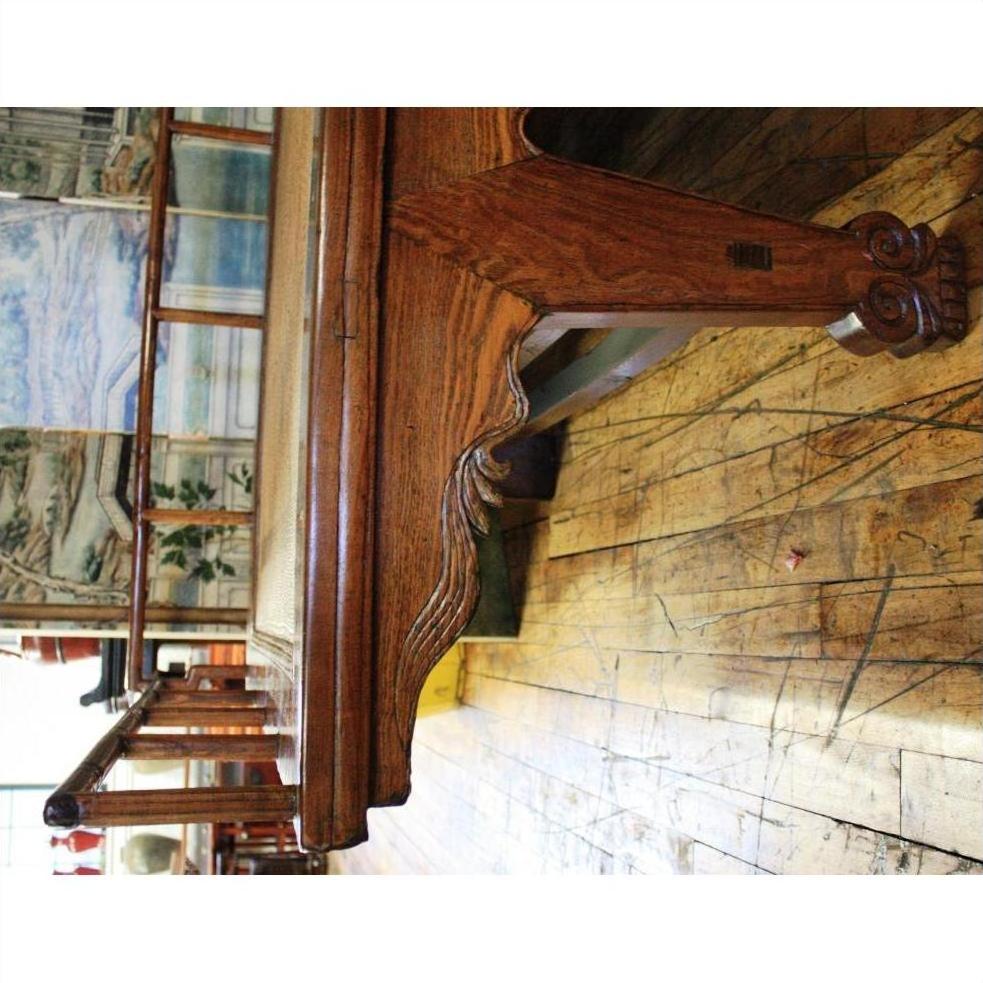 Dark wood Chinese daybed with ornate legs on a worn wooden floor, murals and windows in the background indoors.