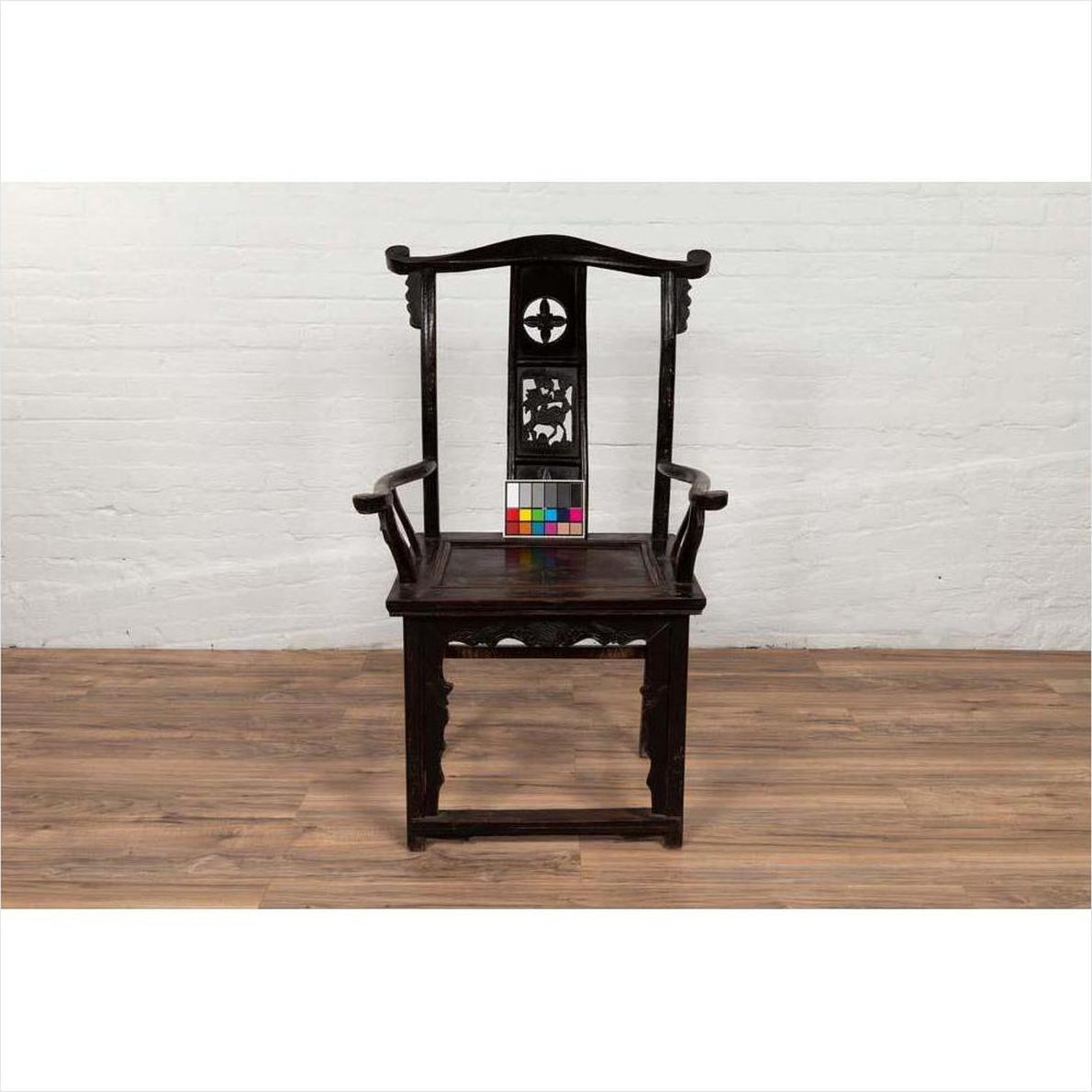 Dark patina Chinese elmwood Dengguayi scholar's chair on wood floor against white brick wall, color chart on seat.