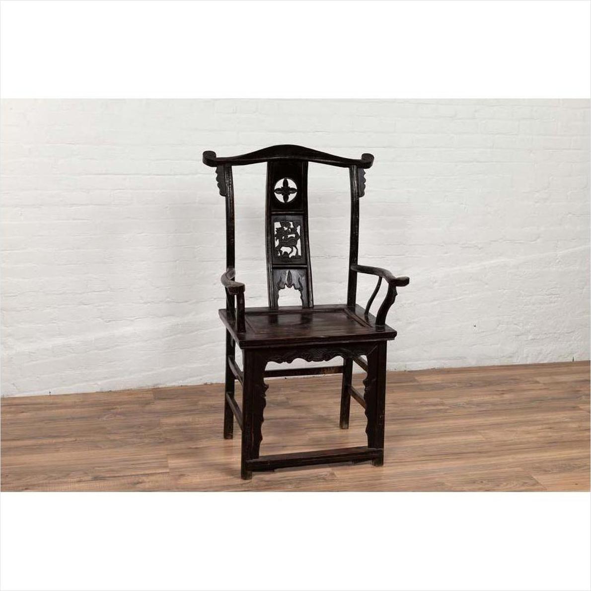 Dark patina Chinese elmwood Dengguayi scholar's chair on wooden floor with white brick wall background.