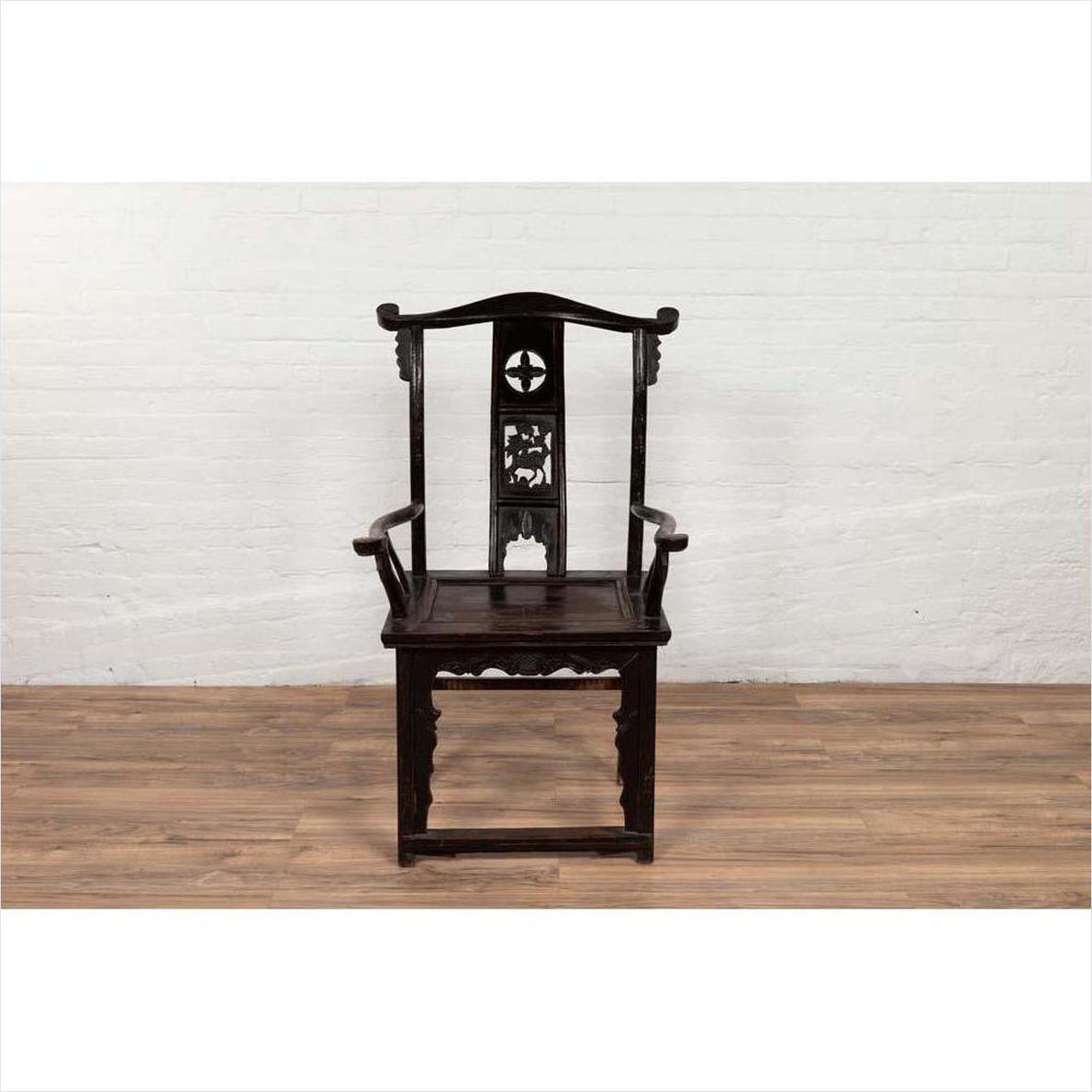 Dark patina Chinese elmwood Dengguayi scholar's chair on wooden floor, white brick wall background.