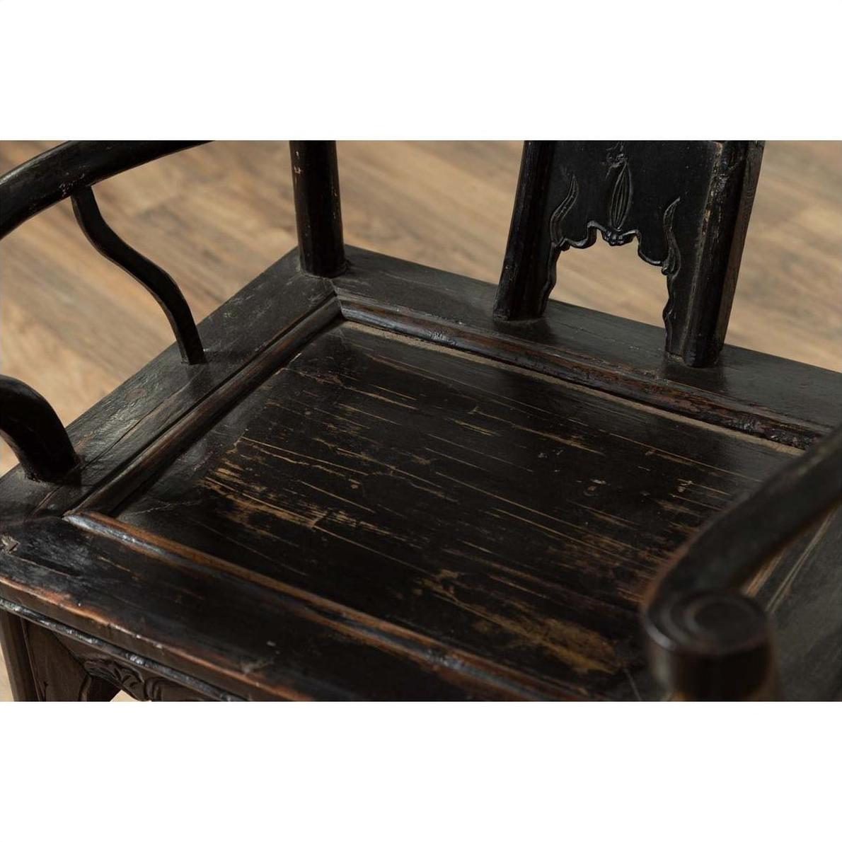 Close-up of dark patina elmwood chair with scratches and carved backrest, 19th century.