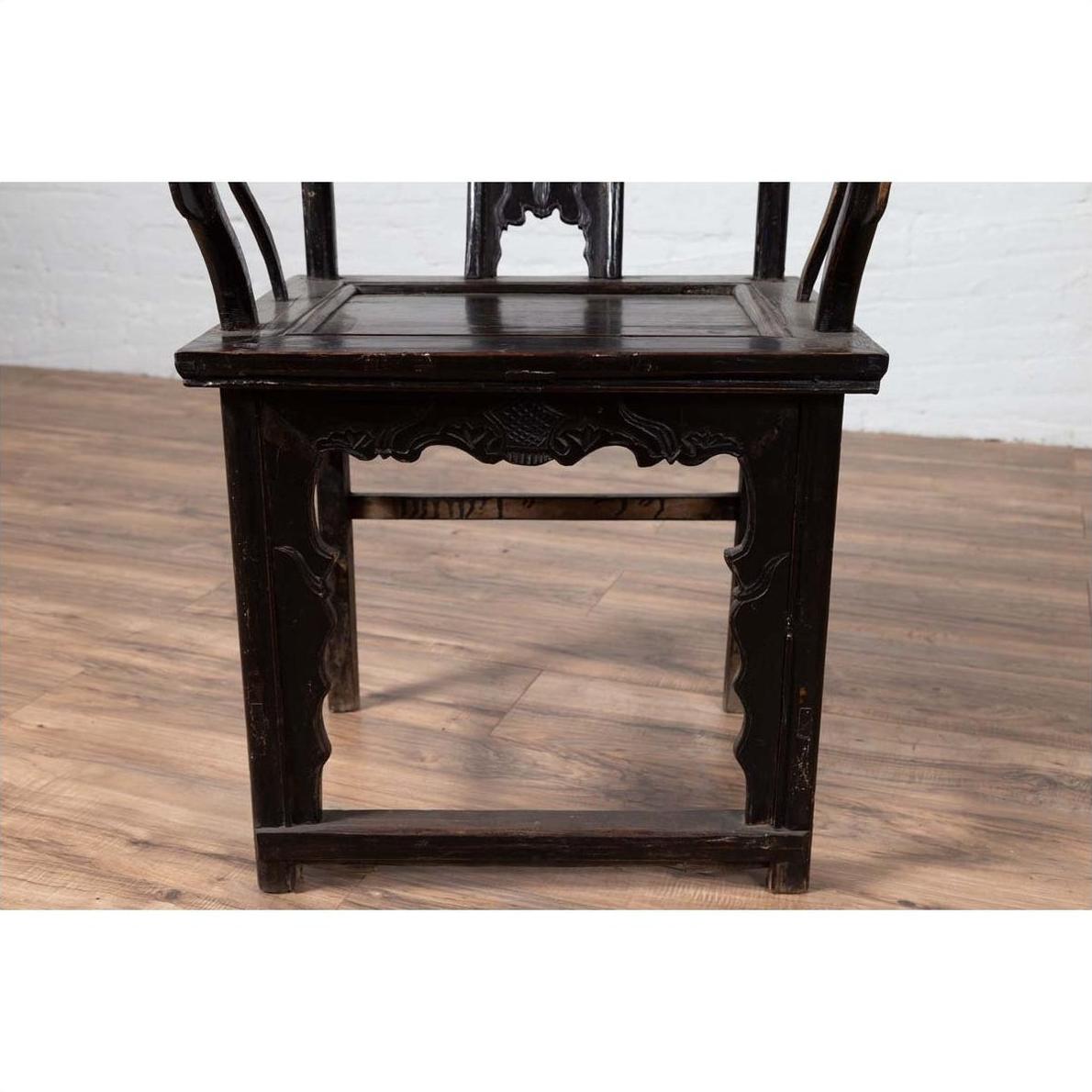 Dark-finish elmwood chair on wooden floor with white brick wall background.