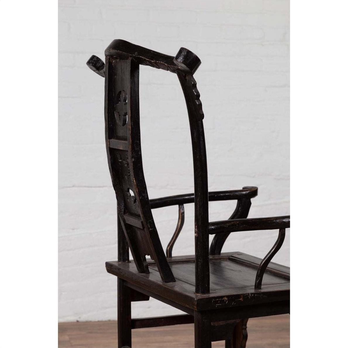 Dark patina elmwood chair with curved backrest, placed indoors against a white brick wall.