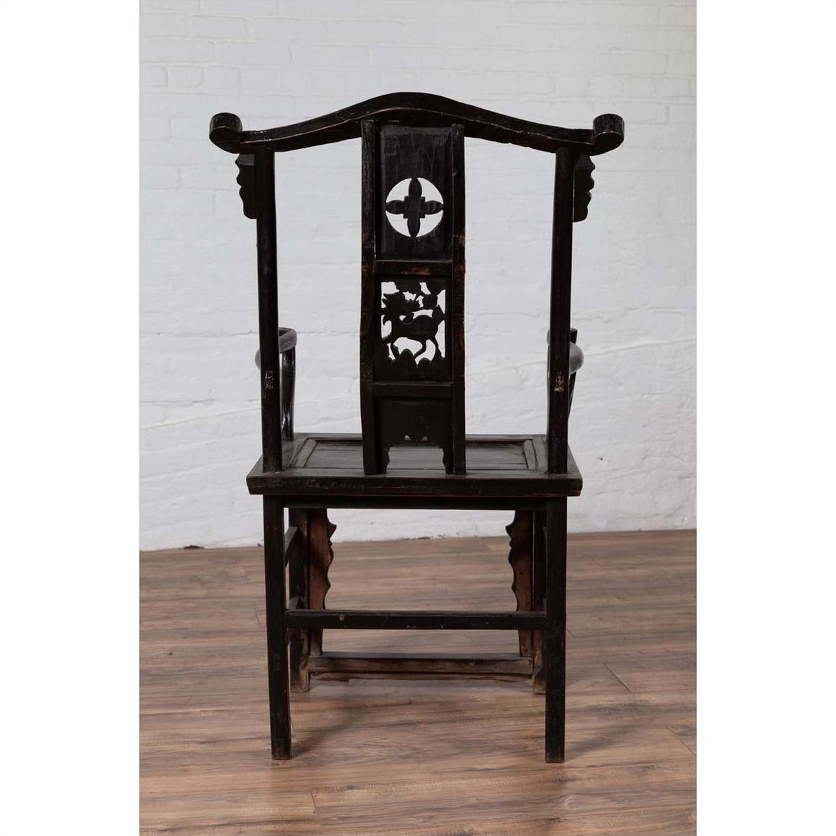 Dark wood chair with ornate backrest, on wooden floor, white wall background.
