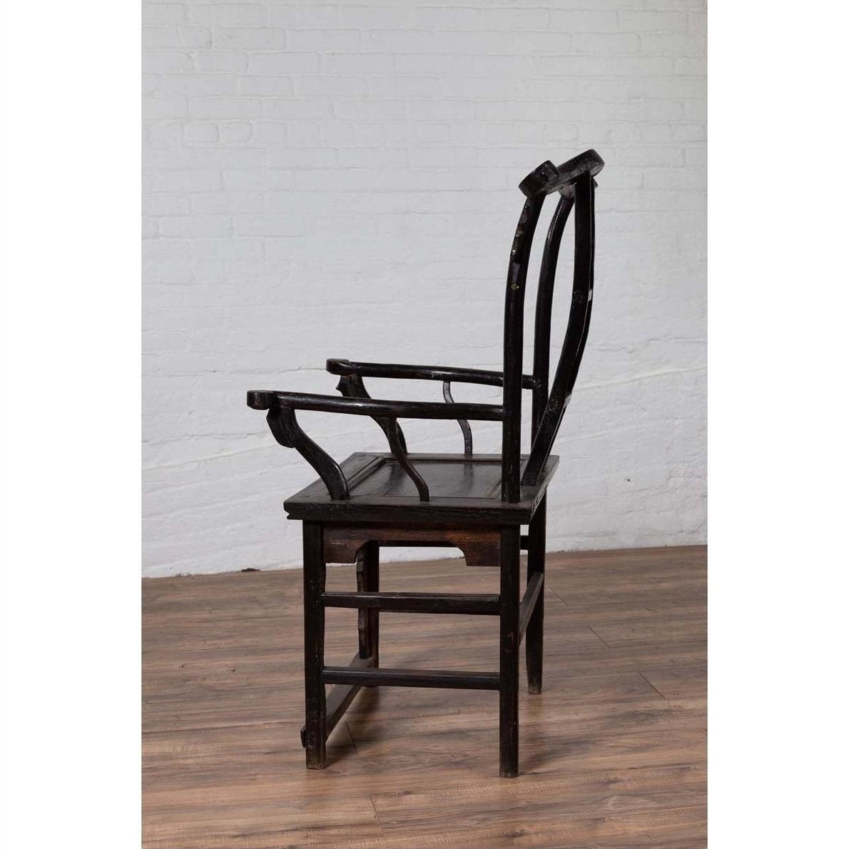 Dark patina elmwood chair side view on wood floor, white brick wall background.
