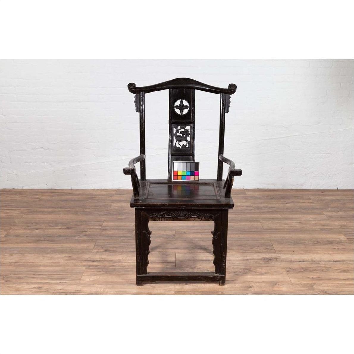 Dark patina elmwood chair with carved details and decorative backrest, shown indoors.