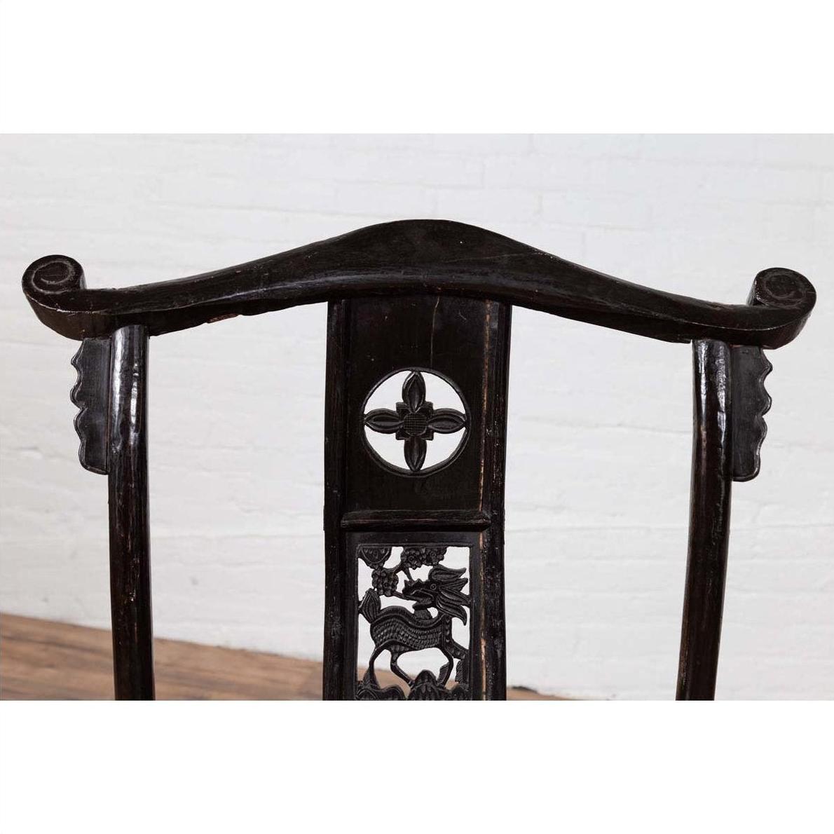 Close-up of dark Chinese elmwood chair with intricate floral and dragon carvings.