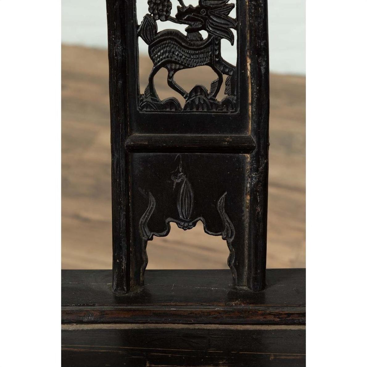 Close-up of dark elmwood chair with dragon carvings and decorative cutouts.
