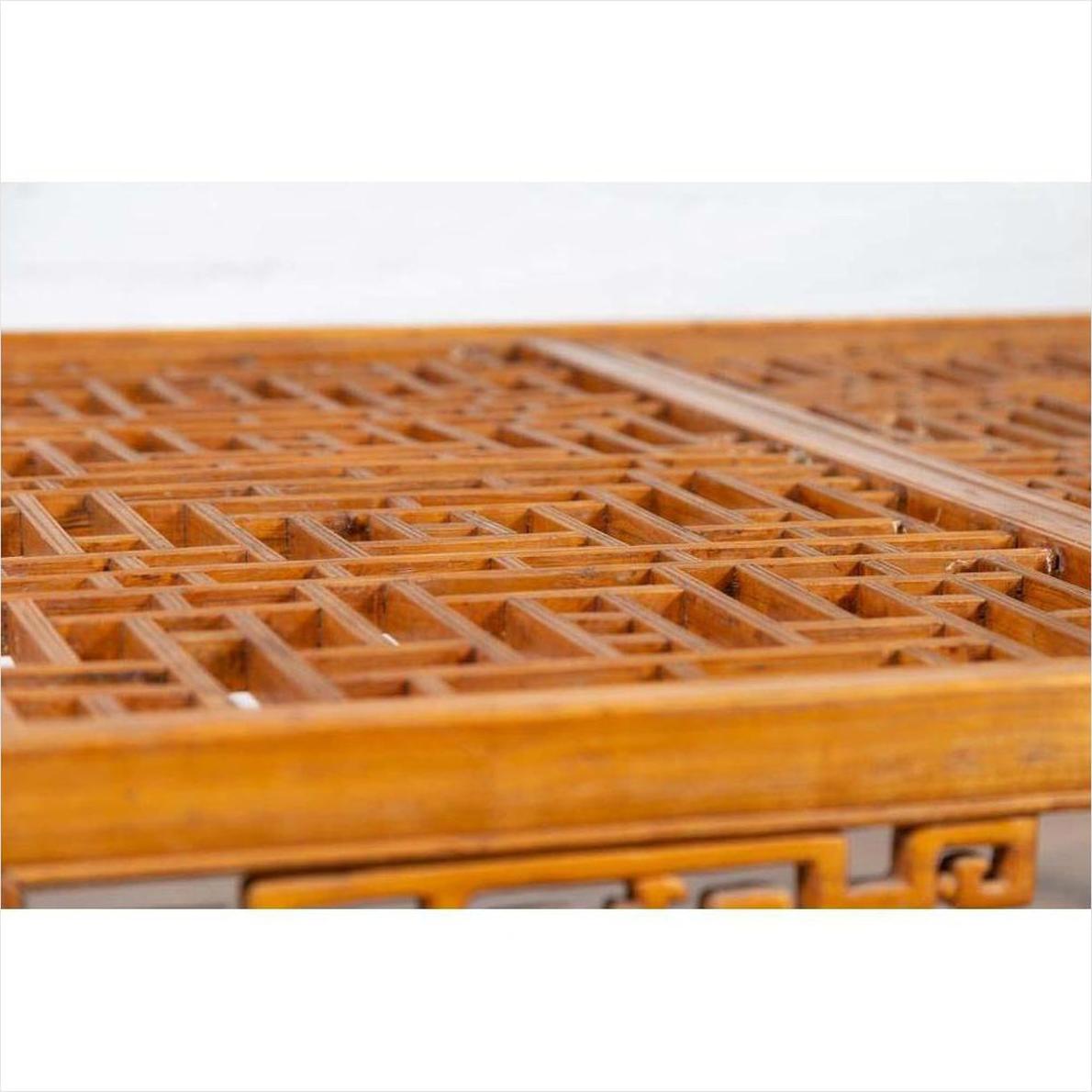 Close-up of warm brown elmwood square coffee table with open fretwork and horse-hoof legs, indoors.