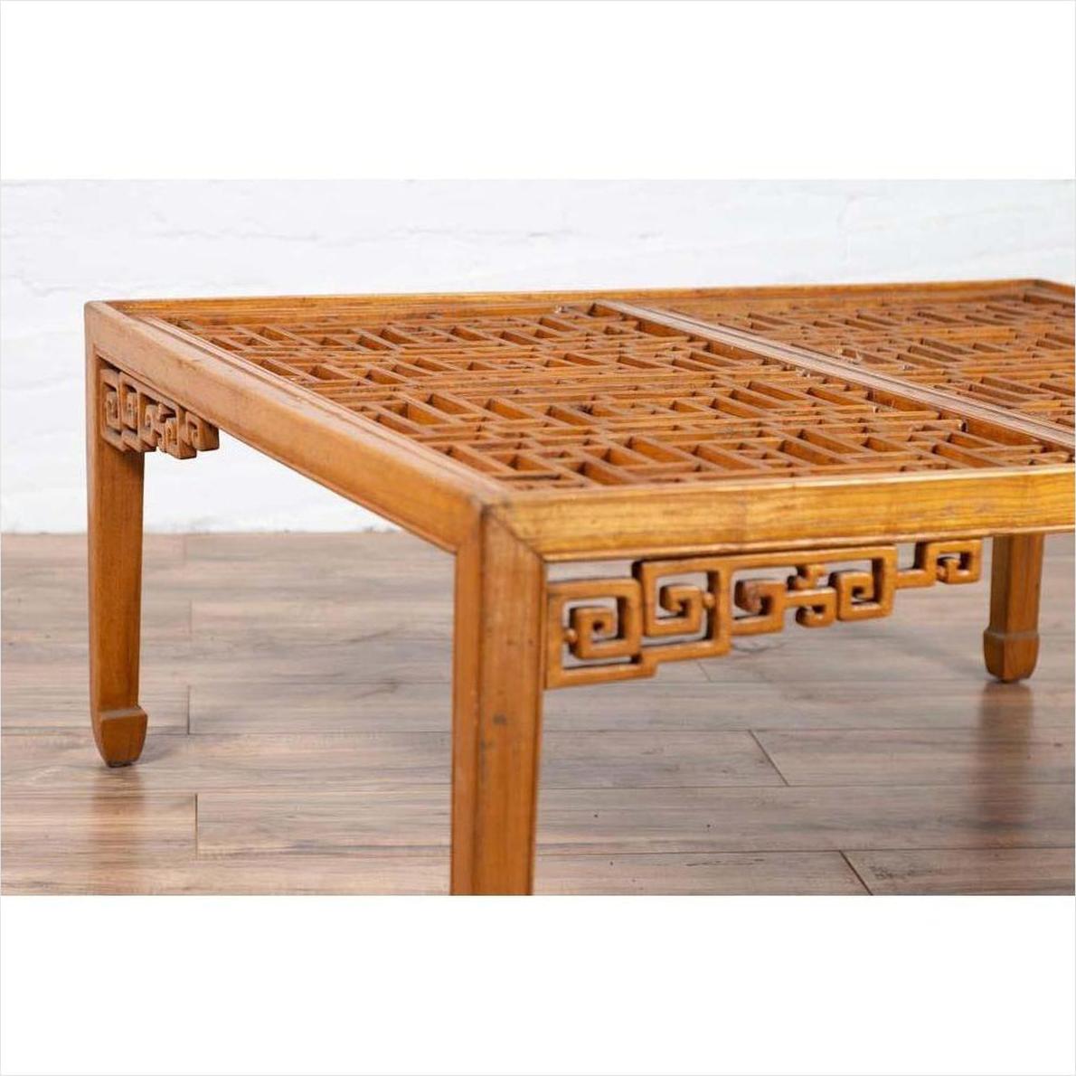 Brown elmwood square coffee table with open fretwork and horse-hoof legs on a wooden floor indoors.