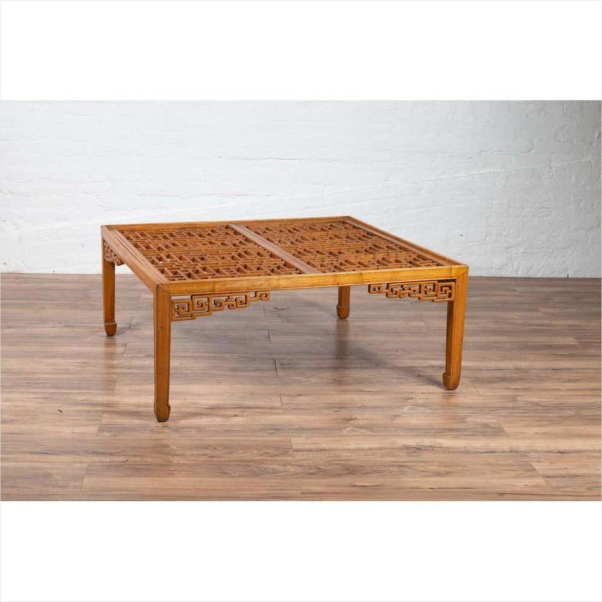 Brown elmwood square coffee table with open fretwork and horse-hoof legs on a wood floor indoors.
