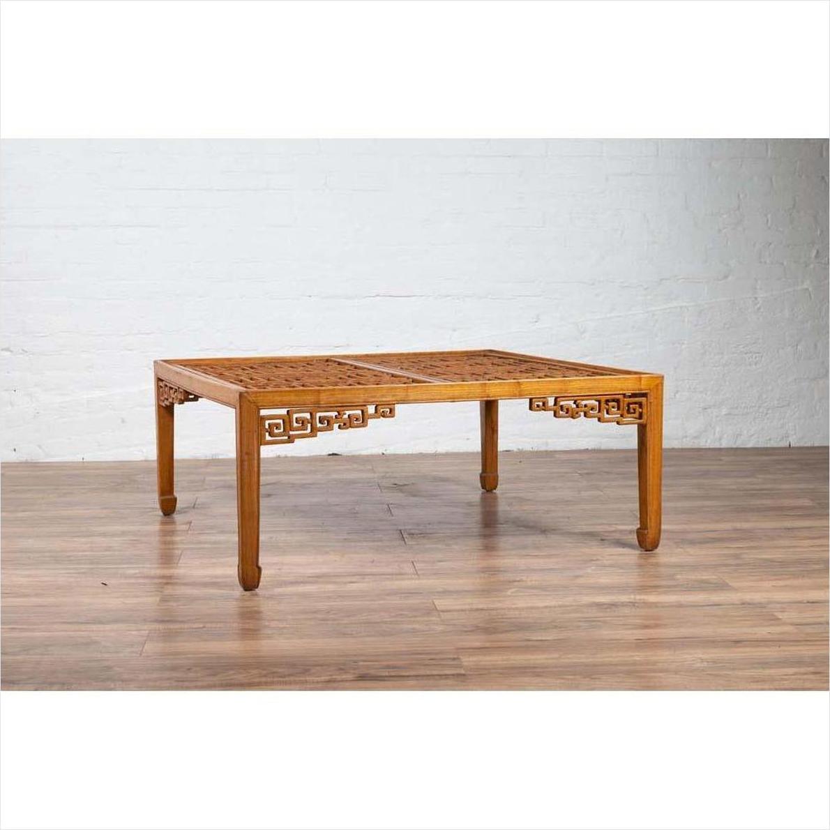Brown elmwood square coffee table with open fretwork and horse-hoof legs on a wood floor.