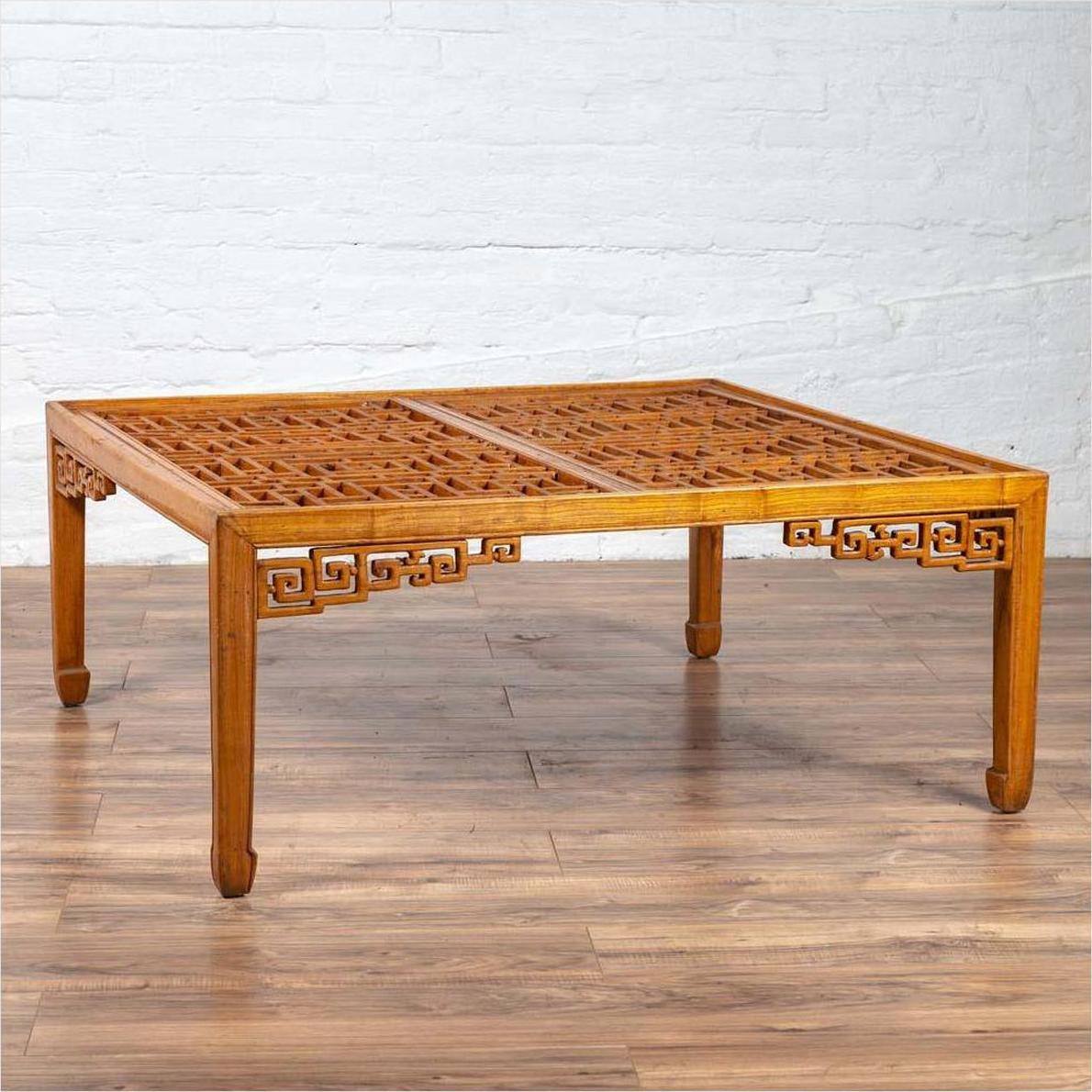 Brown elmwood square coffee table with open fretwork and horse-hoof legs, indoor setting.