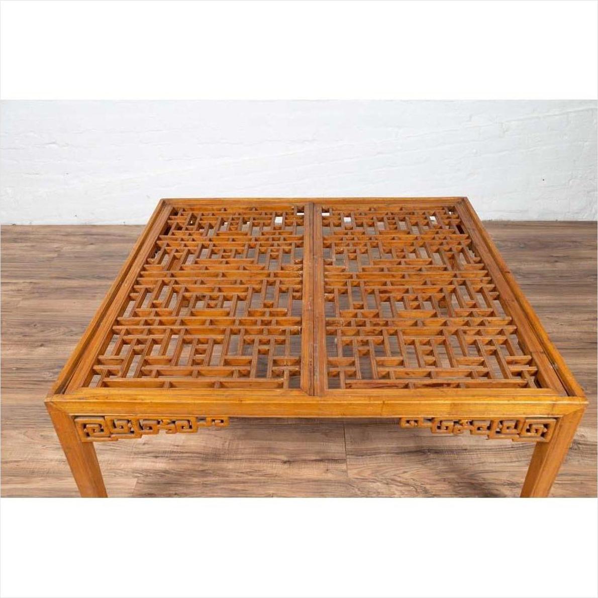 Brown elmwood square coffee table with open fretwork and horse-hoof legs on a wooden floor indoors.