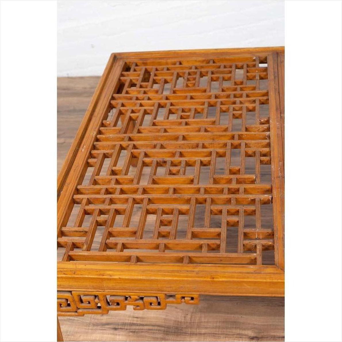 Brown elmwood square coffee table with open fretwork and horse-hoof legs on a wood floor indoors.