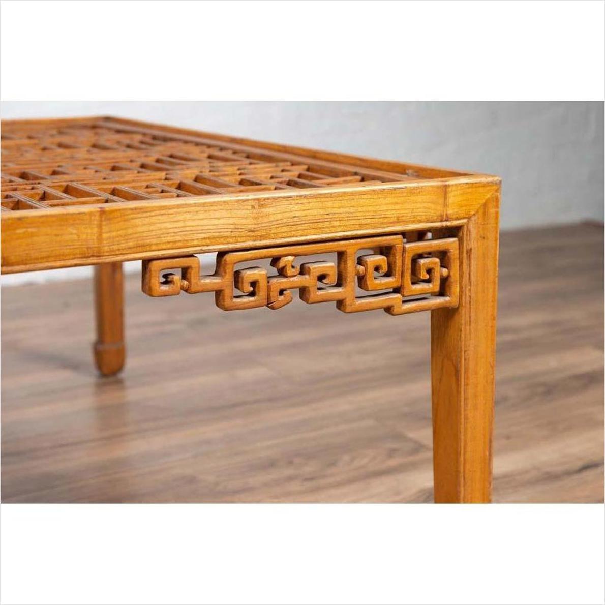 Close-up of brown elmwood square coffee table with open fretwork and horse-hoof legs on a wooden floor.