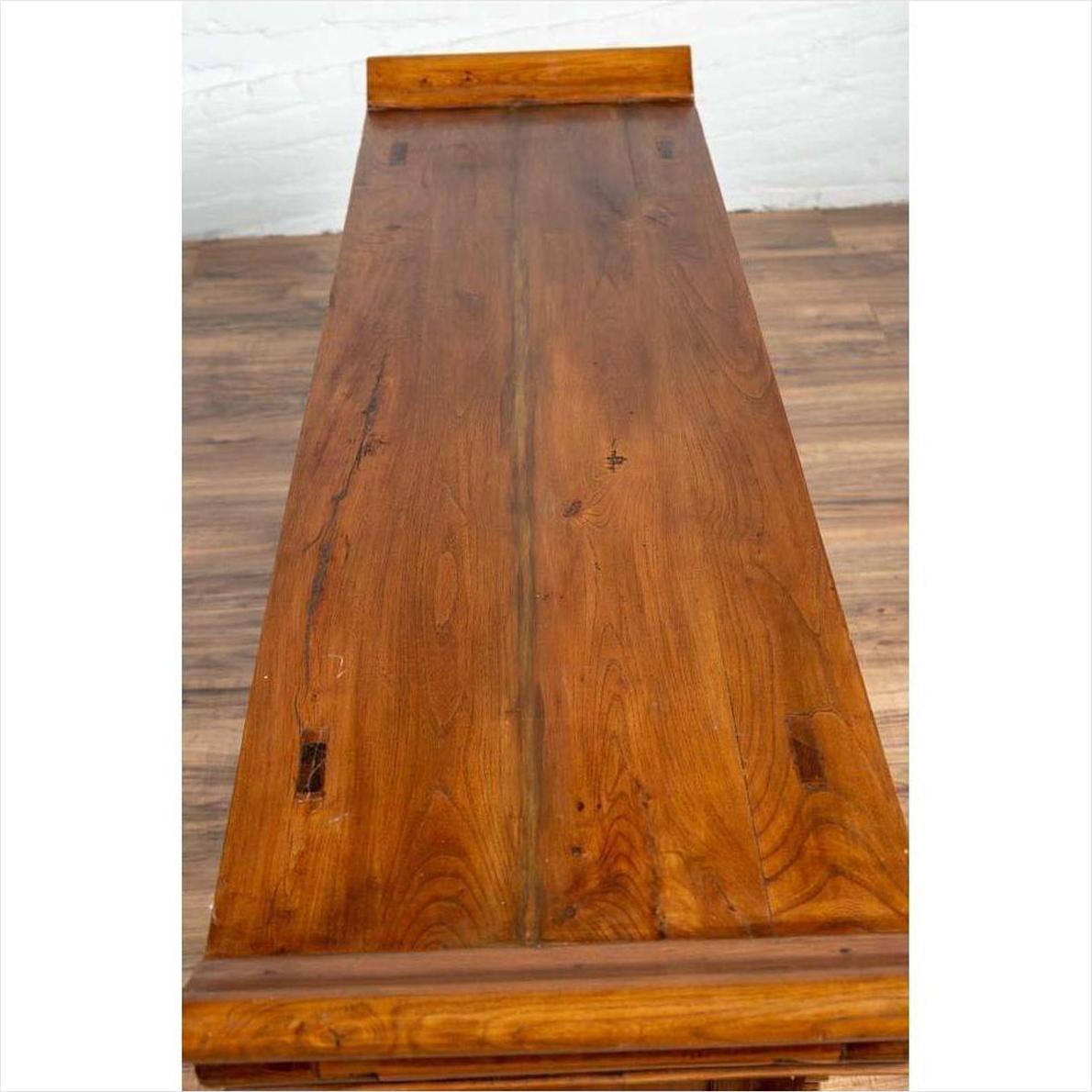 Brown glossy wooden table next to a brown Chinese Elmwood two-door low cabinet with everted flanges indoors.