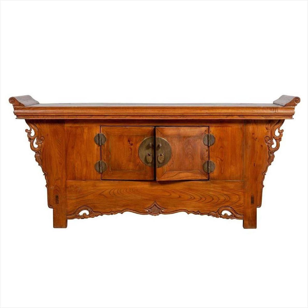 Brown elmwood two-door low cabinet with everted flanges and scrolls, central doors visible, indoors setting.