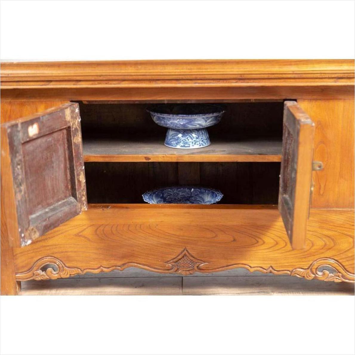 Brown elmwood two-door low cabinet with everted flanges, doors open showing blue and white ceramics inside.