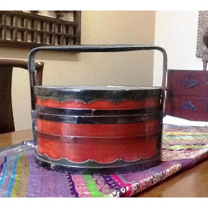 Brown bamboo Chinese food basket with handle on colorful fabric table runner, close-up.