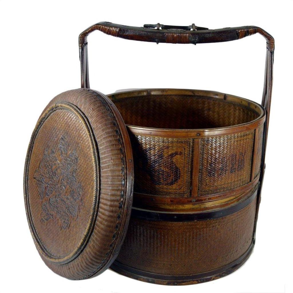 Brown wicker Chinese wedding basket with tall handle and round lid, decorative pattern visible, close-up view.