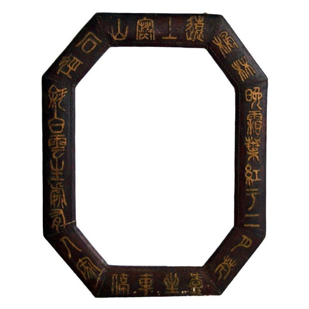 Close-up of octagonal dark wood Chinese leather frame with gold calligraphy on white background.