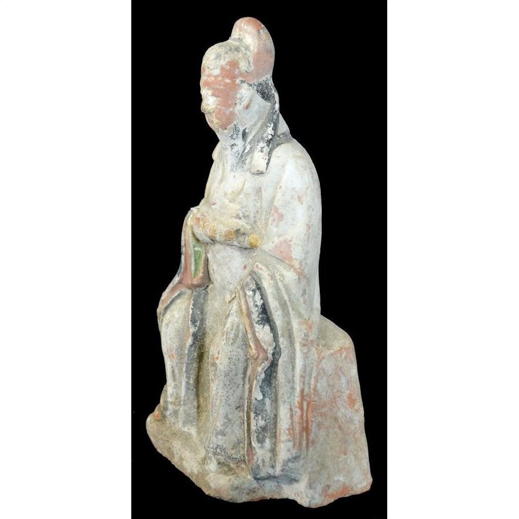 Terracotta Ming Dynasty seated court figure statuette in robes with hands on lap, close-up against black background.