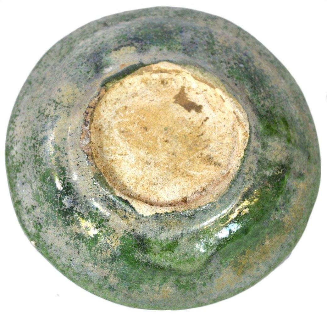 Close-up of a weathered ceramic bowl base with mottled green glaze, resembling Chinese Ming Dynasty food plates.