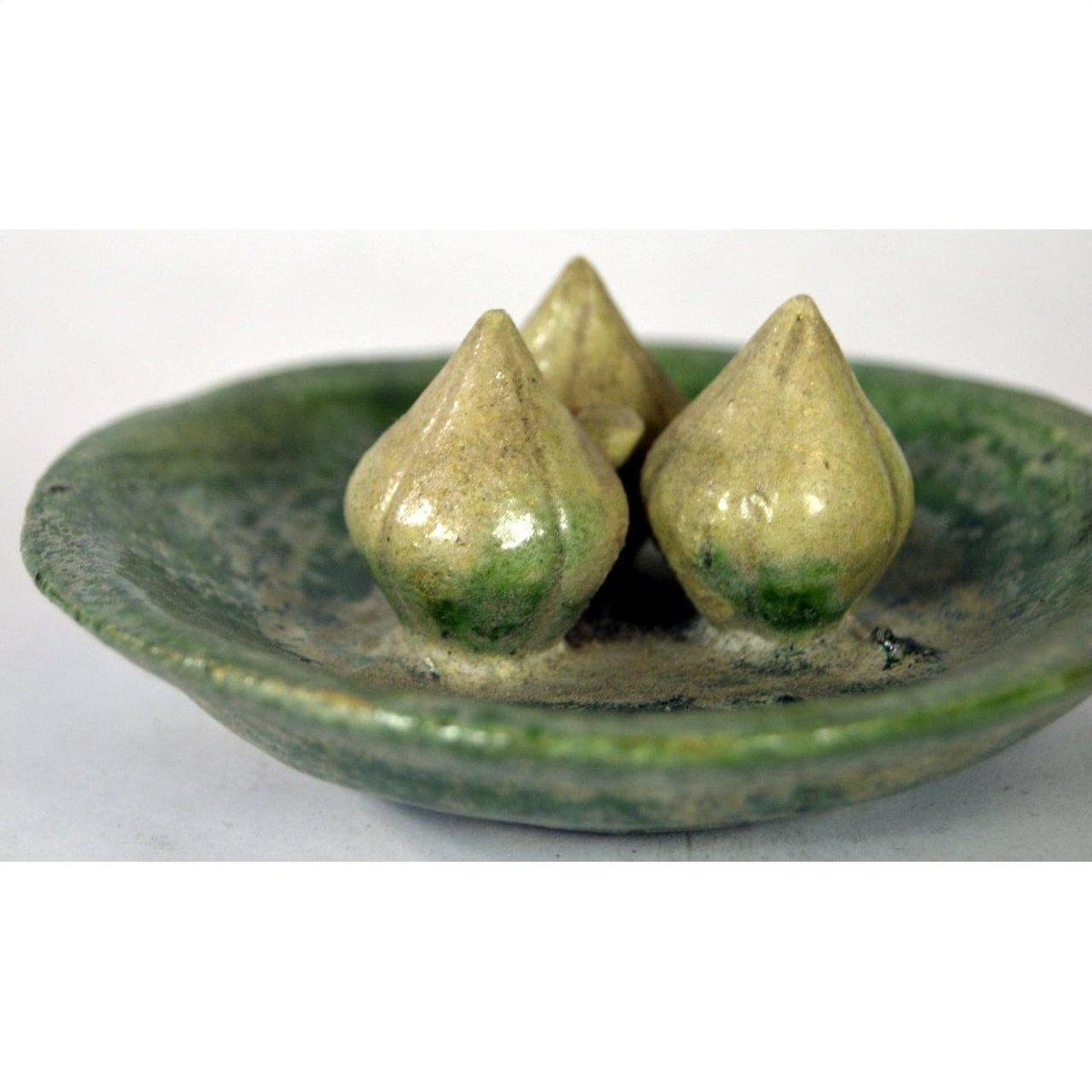 Green glazed ceramic Ming Dynasty plate with three rustic, cone-shaped decorations, close-up view.