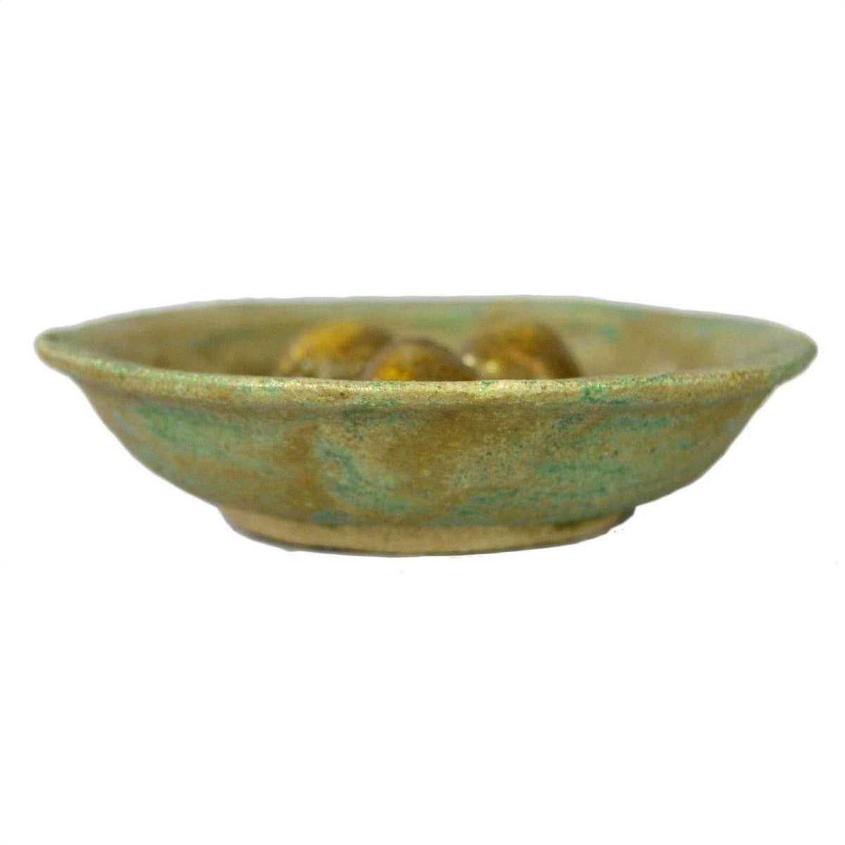 Rustic green ceramic Chinese Ming Dynasty plate with three small brown objects on a white background.