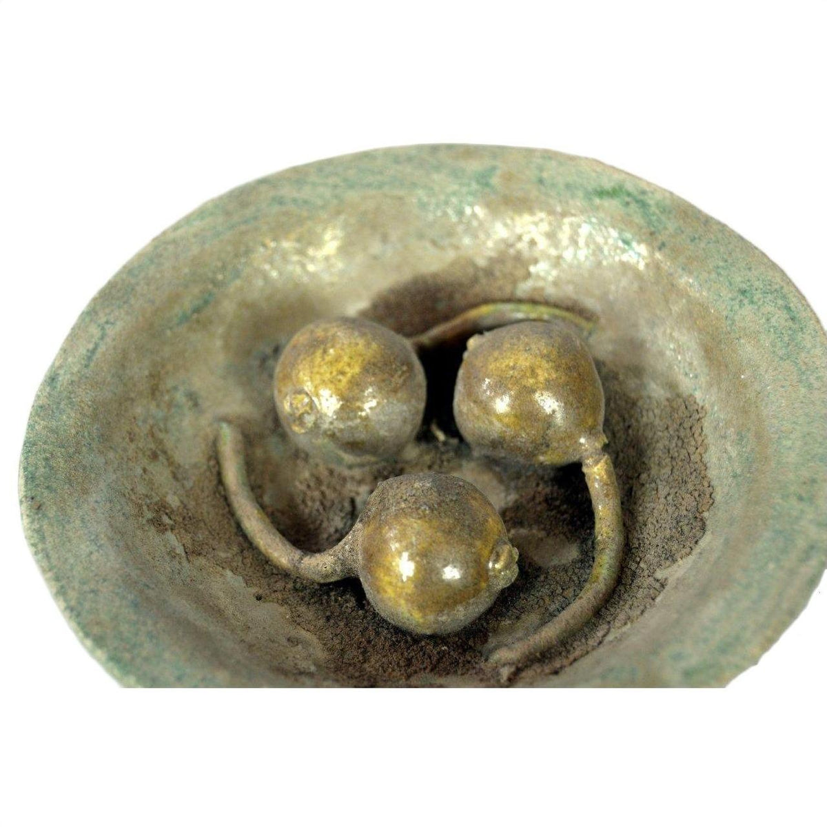 White porcelain Ming Dynasty plate with three bronze pomegranates and stems, close-up on a white background.