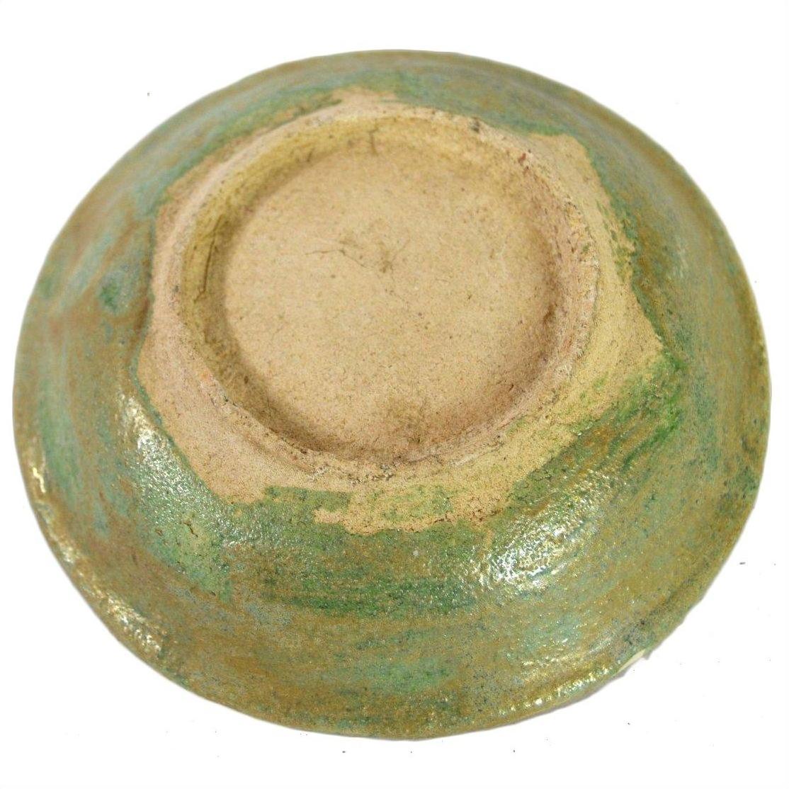 Close-up of greenish glazed ceramic Ming Dynasty plate with unglazed foot, antique Chinese dish style.