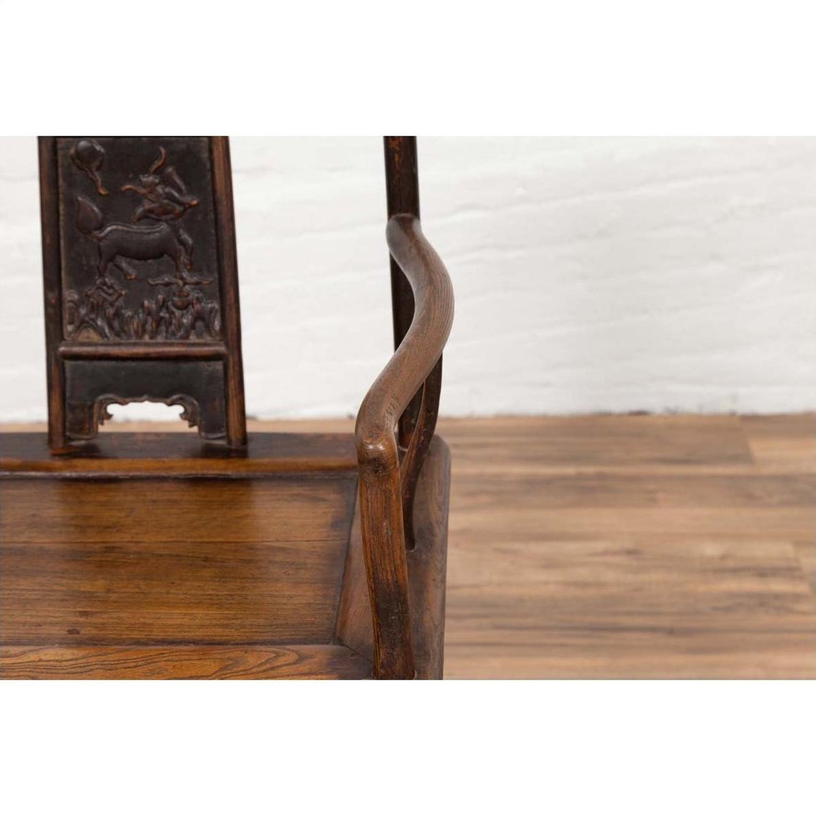 Close-up of brown elmwood Ming Dynasty chair with carved animal design on the backrest.