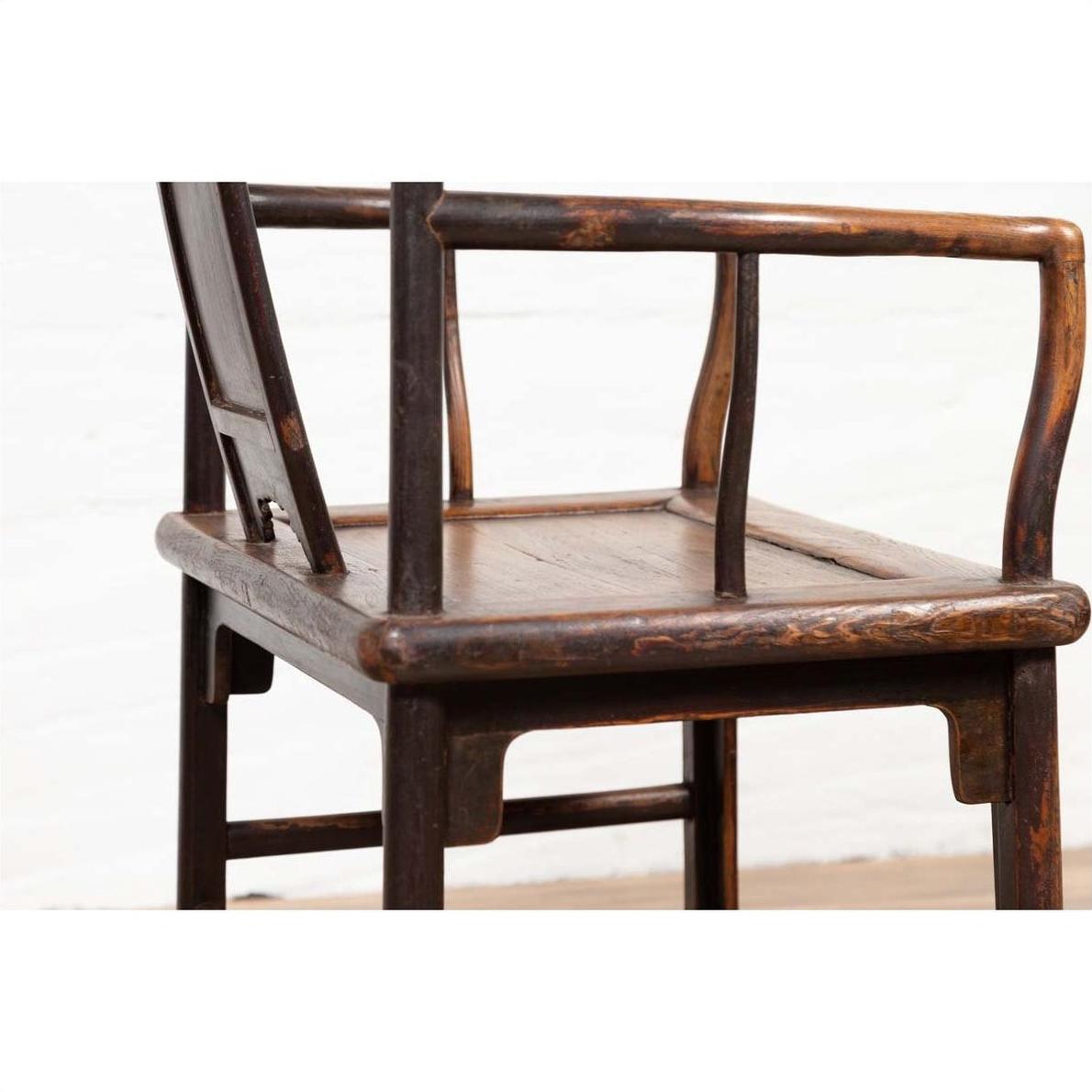 Close-up of brown elmwood Ming Dynasty style chair with curved backrest and armrests on white background.