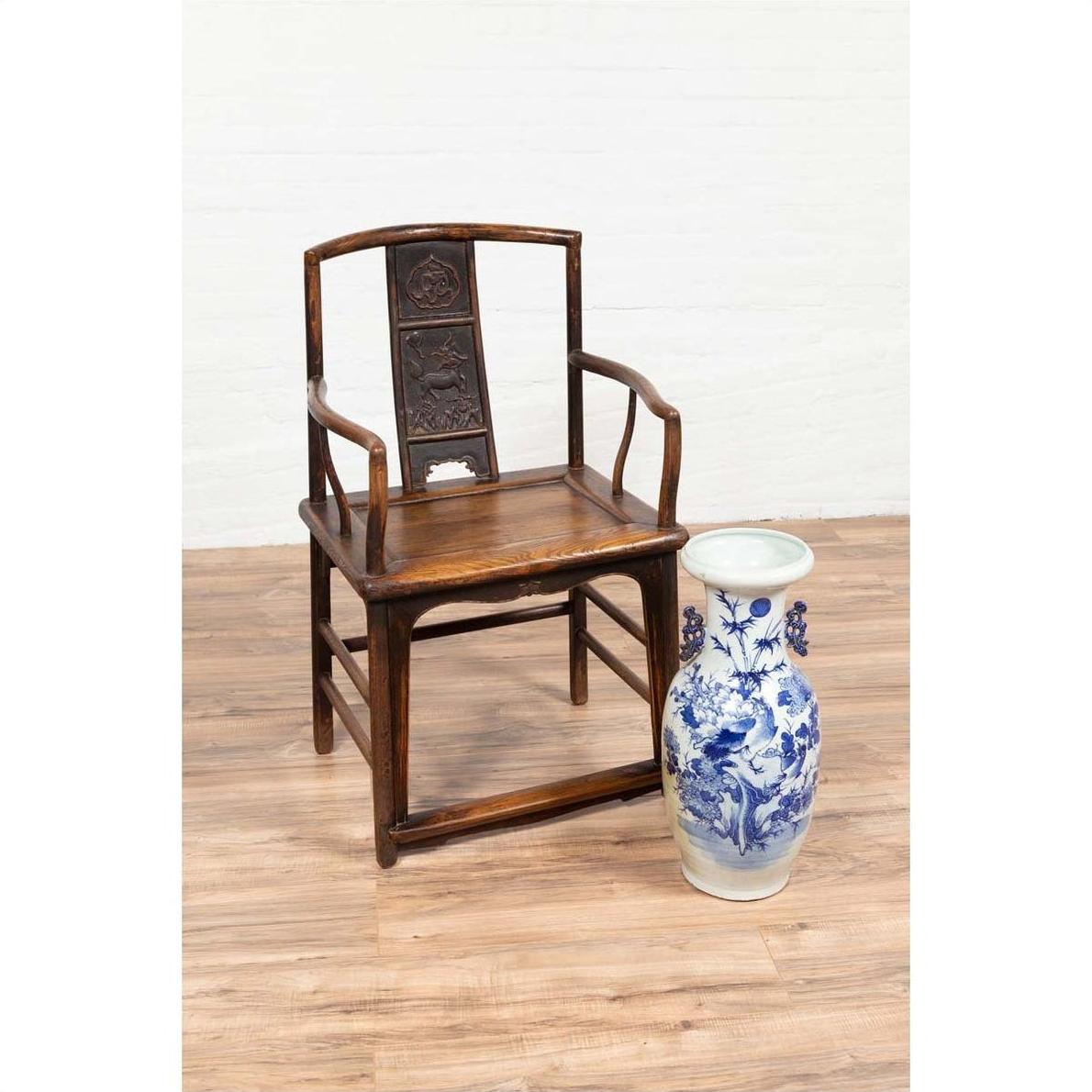 Brown elmwood Ming Dynasty chair beside white porcelain vase on wooden floor, indoors.